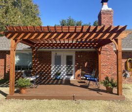 Beautiful backyard with a wooden pergola, outdoor seating, and potted plants for relaxing outdoor space. Wooden pergola deck with outdoor seating and potted plants in backyard.