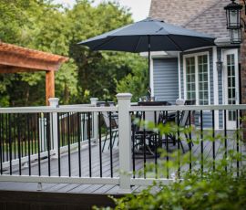 A stylish outdoor deck with a black umbrella, seating area, and safety railing, perfect for relaxing and entertaining in a backyard setting. deck builder Oklahoma city deck builder Tulsa