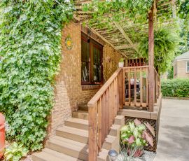 Beautifully crafted wooden porch with vibrant plants and greenery, enhancing curb appeal and outdoor living space. Custom wooden porch with lush greenery and decorative plants.