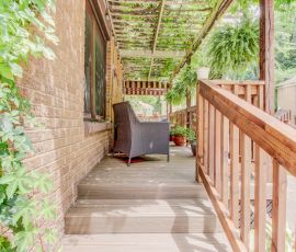 Inviting wooden porch with seating area and lush plants, ideal for outdoor leisure and enjoying nature. Cozy wooden porch with seating and greenery, perfect for outdoor relaxation.