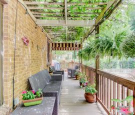 Charming wooden porch featuring lush hanging ferns, vibrant potted flowers, and comfortable seating, perfect for outdoor relaxation and gatherings. Inviting outdoor porch with wooden railing, hanging ferns, and colorful potted plants for relaxing o.