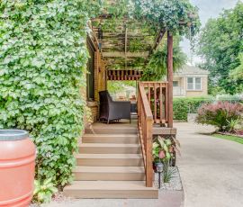 Beautiful backyard deck with stairs, seating area, and lush greenery. Deckworks custom outdoor deck with stairs and shaded lounge space.