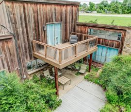 default Deck with wooden railing and outdoor seating area attached to a rustic wooden building, surrounded b.
