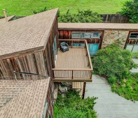 default Elevated view of a wooden deck with outdoor seating and lush greenery.