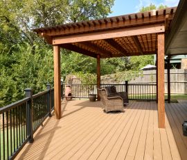 Beautiful backyard deck with pergola, outdoor seating, and scenic greenery for relaxing outdoor gatherings. Custom wooden deck with pergola and outdoor seating in a backyard setting.