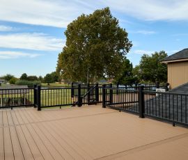 Beautiful backyard deck with modern black railing, perfect for outdoor gatherings and relaxation. Stylish outdoor deck with black railing and spacious wooden flooring in a suburban backyard.