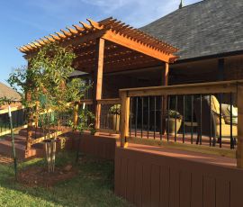 Beautiful backyard deck with a wooden pergola, outdoor furniture, and lush landscaping. Outdoor deck with pergola and seating area for relaxing and entertaining.