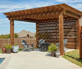 Stylish backyard pergola with seating area, wooden slats, and decorative planters for outdoor relaxation. Elegant wooden pergola with slatted privacy screen, outdoor seating, and potted plants in a backyard.
